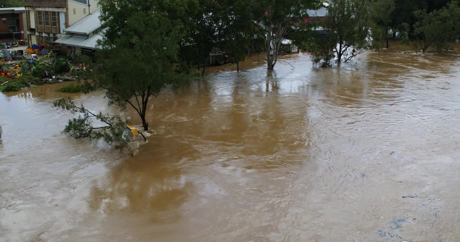 A part of a city with a brown flood with water flowing strongly