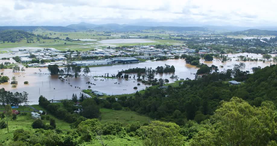 A suburban community is flooded and surrounded by green vegetation at midday