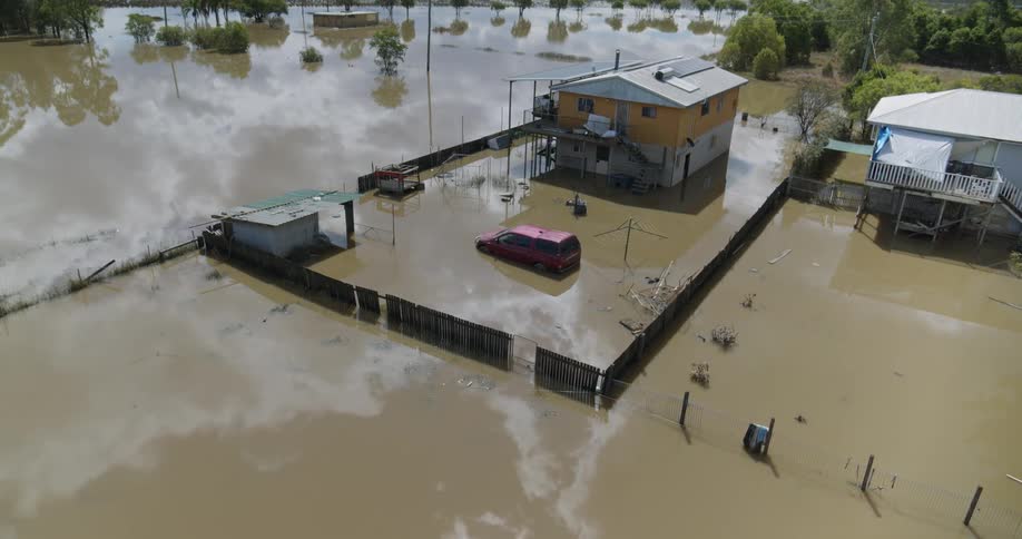 Aerial view of a stilted houses partially submerged in muddy floodwaters