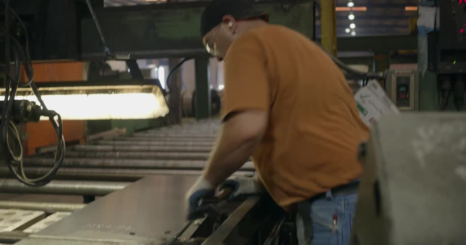 A man in a factory using tools to work on a metal sheet