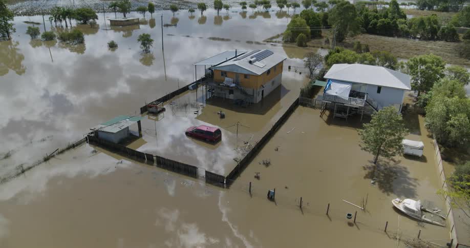 Aerial view of a residential area submerged in muddy floodwaters with houses cars and fences partially underwater
