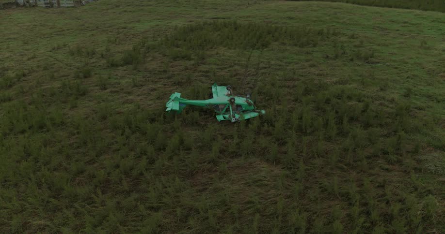 Small aircraft wreckage in an open field with low vegetation