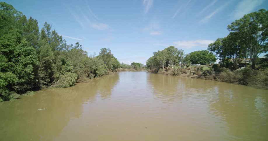 Wide muddy river between dense vegetation and inhabited area