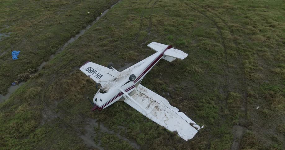 Broken down airplane after a crash next to a water stream outdoors during day time