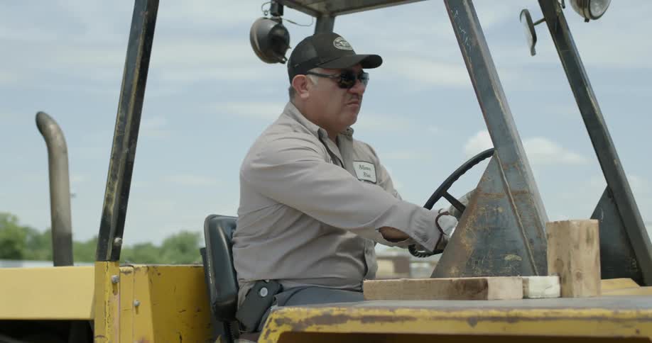 A man drives a construction vehicle backwards