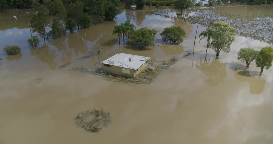 House partially submerged by flooding in a rural area surrounded by trees