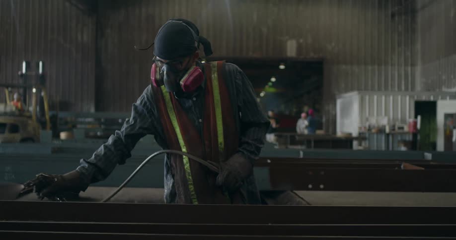 A man wearing a respirator mask and spraying materials in a workshop