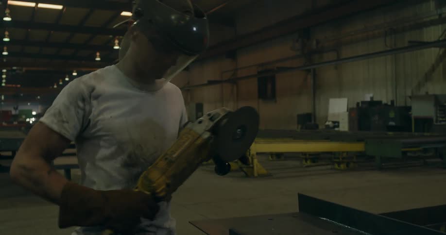 A man is sawing some steel in a workshop