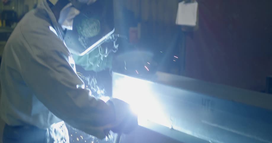 A man closes his welding mask and begins working