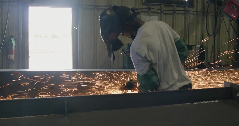 Sparks fly around a welder in a shop