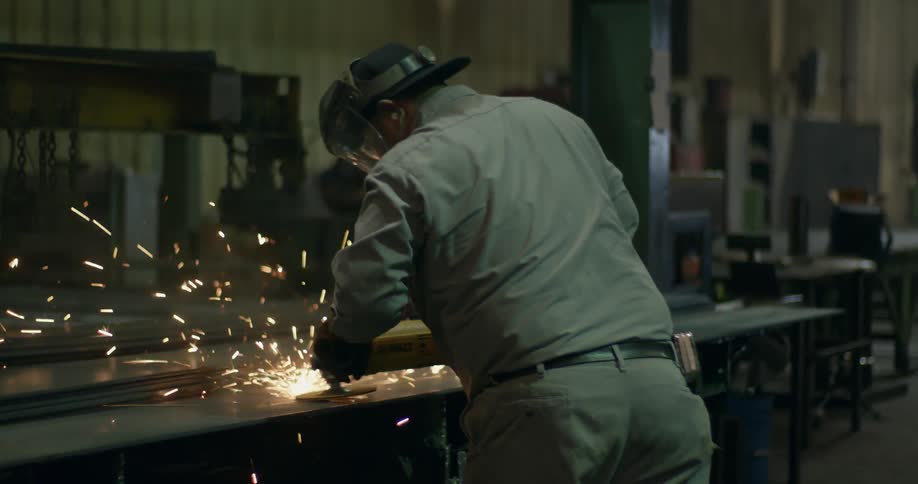 A man uses a power tool to cut metal