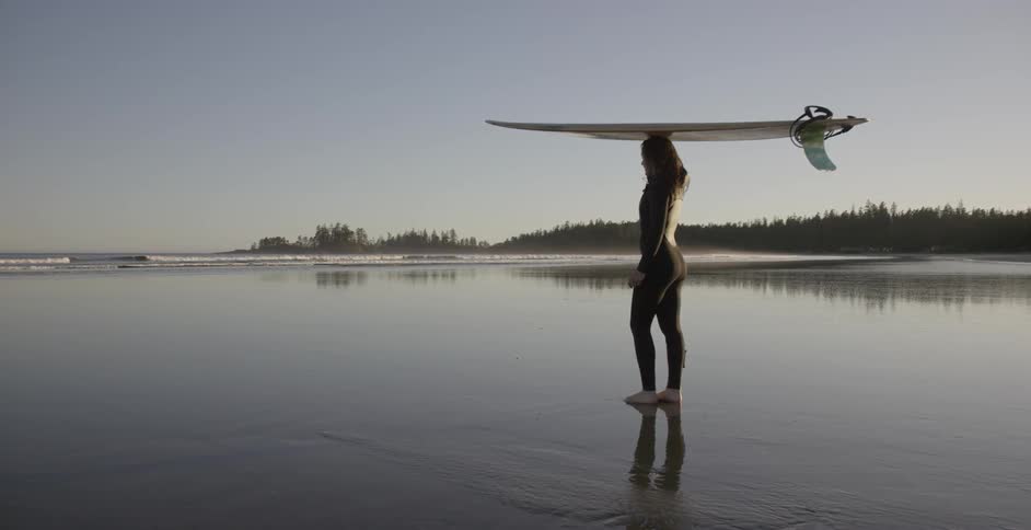 A woman has a surfboard on her head by the shore