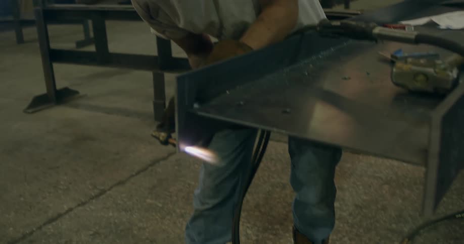 A man uses a torch on metal beams