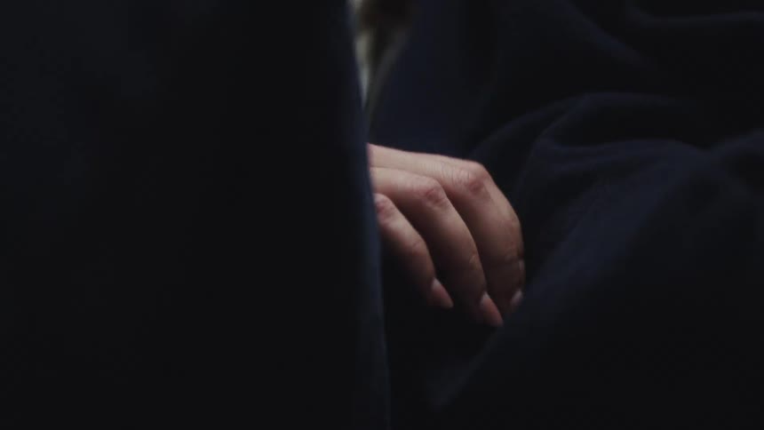 Female hand caressing another person next to her through a blanket indoors