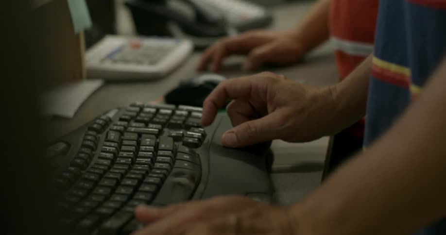Person using computer mouse and typing on keyboard at desk