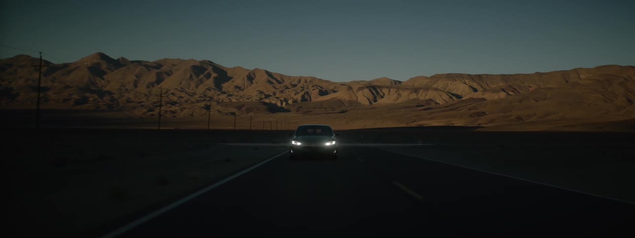 Sports car driving on highway surrounded by mountain wilderness