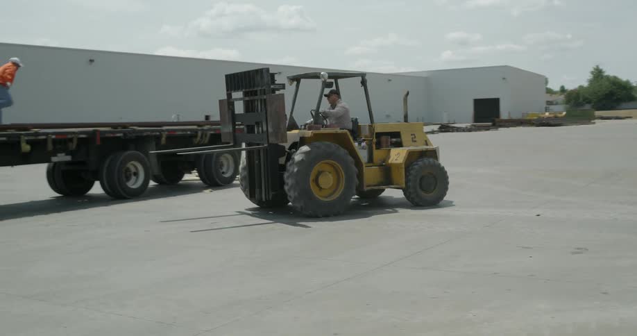 A fork lift backs up after dropping something off on a trailer