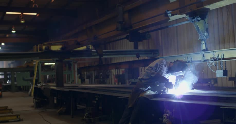 A man is welding a long beam