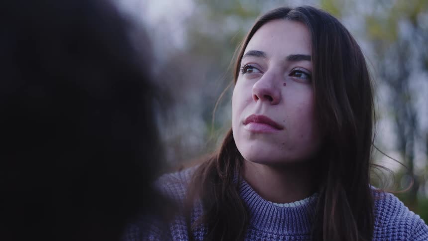 Couple appears in alternating focus outdoors with one person looking toward the horizon while the other stands in the background