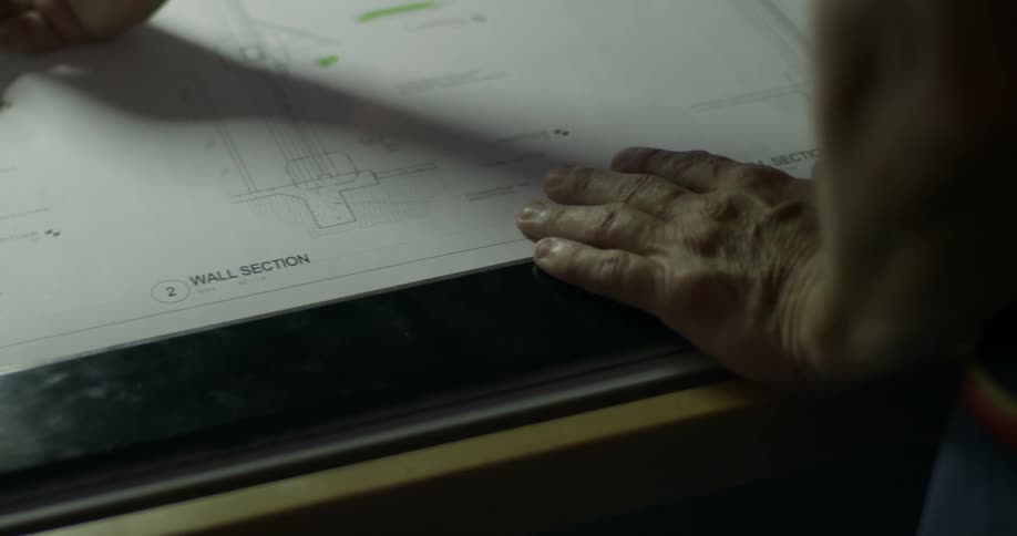 A person uses a pencil to point out details on a building plan