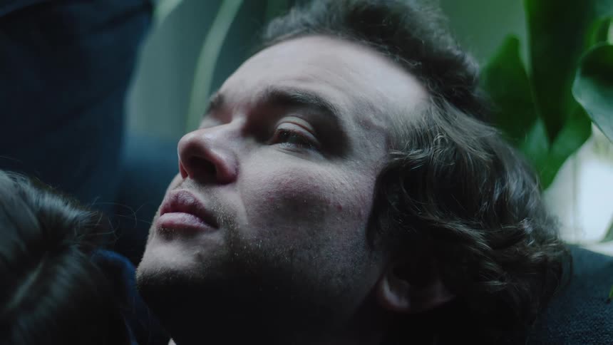 A man lies on his back gazing upward with a thoughtful expression eyes gently blinking in quiet contemplation