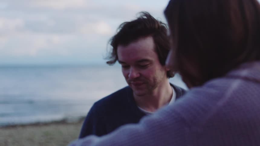 A man and woman throwing rocks into the ocean