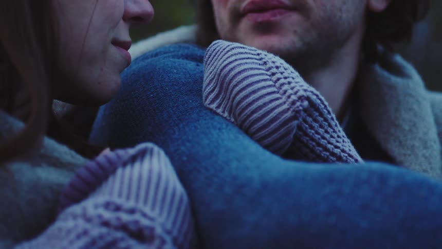 Woman with closed eyes resting her head on a mans shoulder outdoors