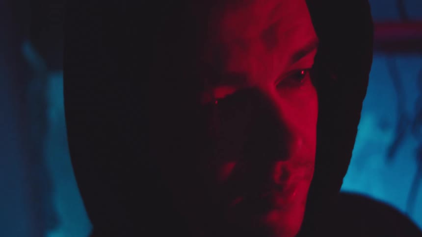 Close up portrait of a young man standing outdoors at night under flickering lights