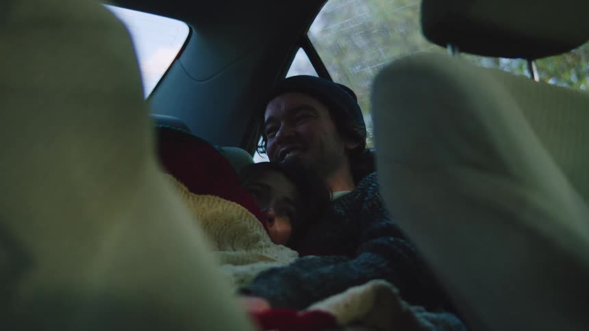 A man and woman cuddling in the back seat of a car