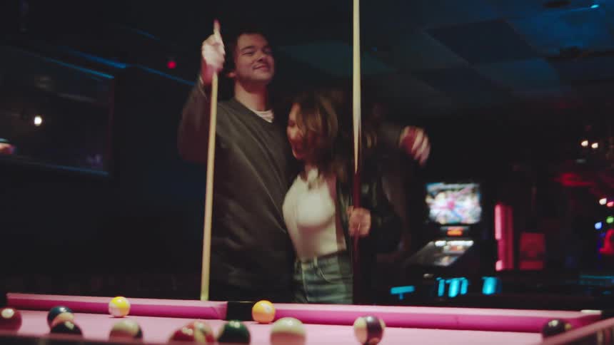 A man and woman playing pool in a bar