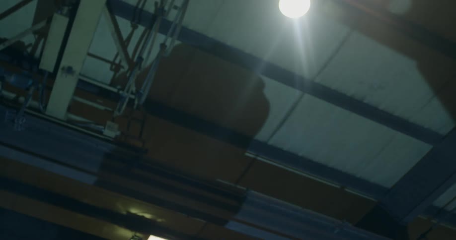 The shadow of a man's head on the ceiling of a dark room with a light overhead