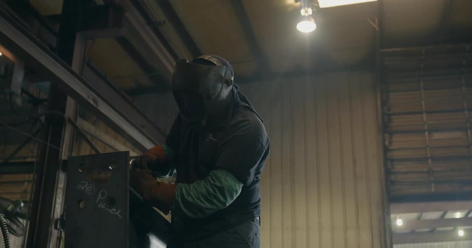 Man wearing welding helmet is welding in a shop