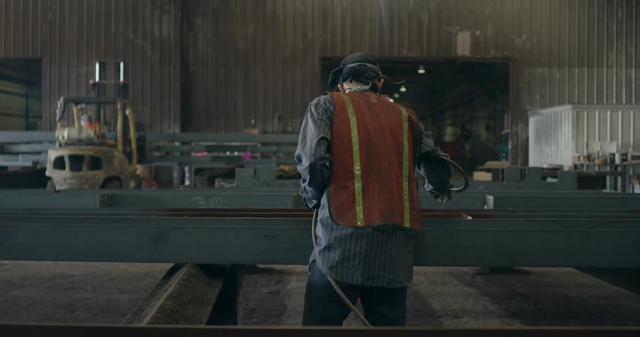 Man using a spray gun to coat something in a large workshop