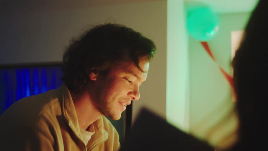 A man blowing out candles on a cake at a party