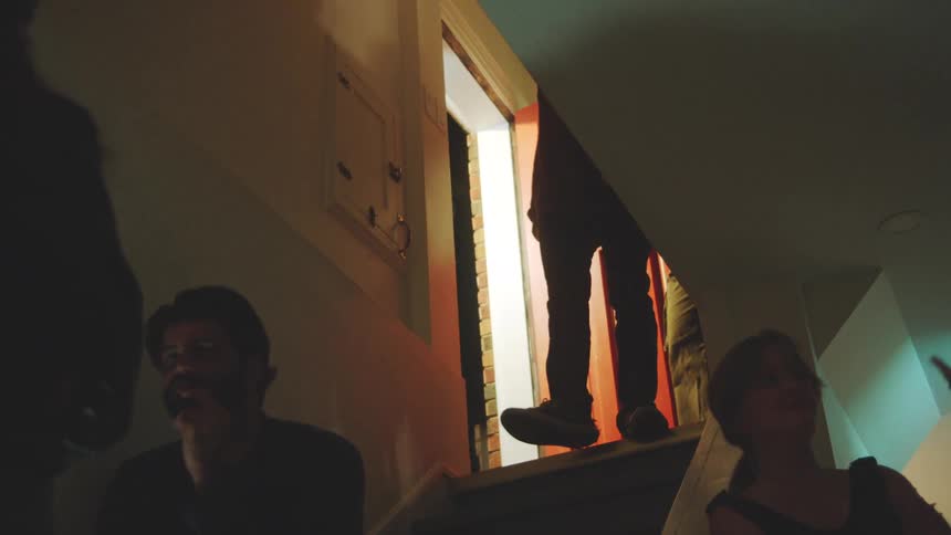 The man enters the home and waves to people at a party