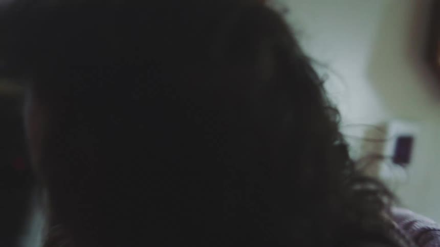 Person hugging another indoors with faces close together