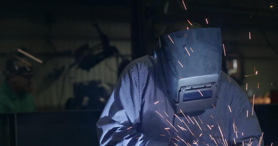 Sparks and smoke fly around a welder