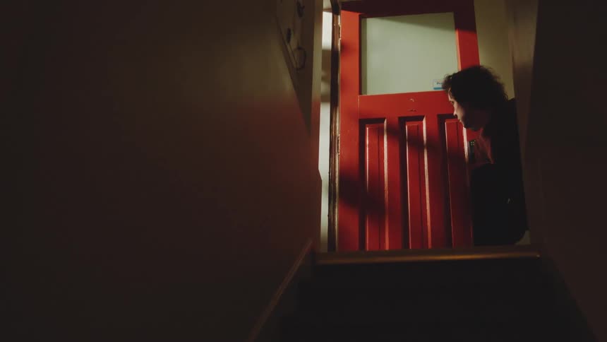 Man crouching at the top of stairs putting on a sneaker