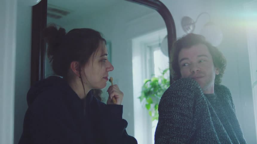 The man looking out the window looks back and smiles at a woman