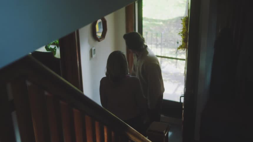 The man enters his home and is hugged by a woman