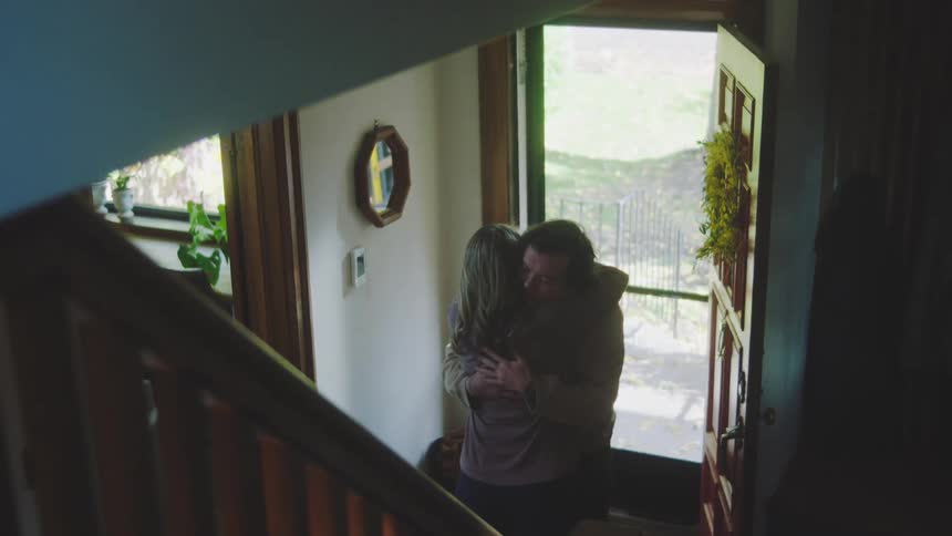 A man coming home and hugging a woman