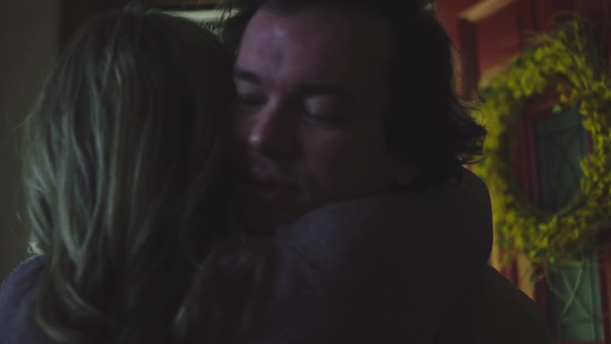 A man and woman hugging in an entryway of a house