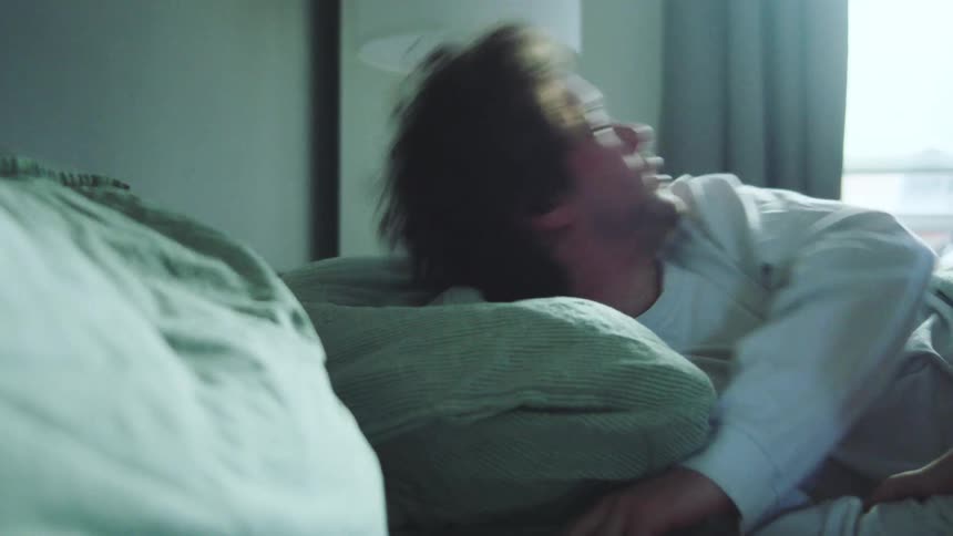 Woman attempts to wake a man sleeping in bed but lies down when he resists