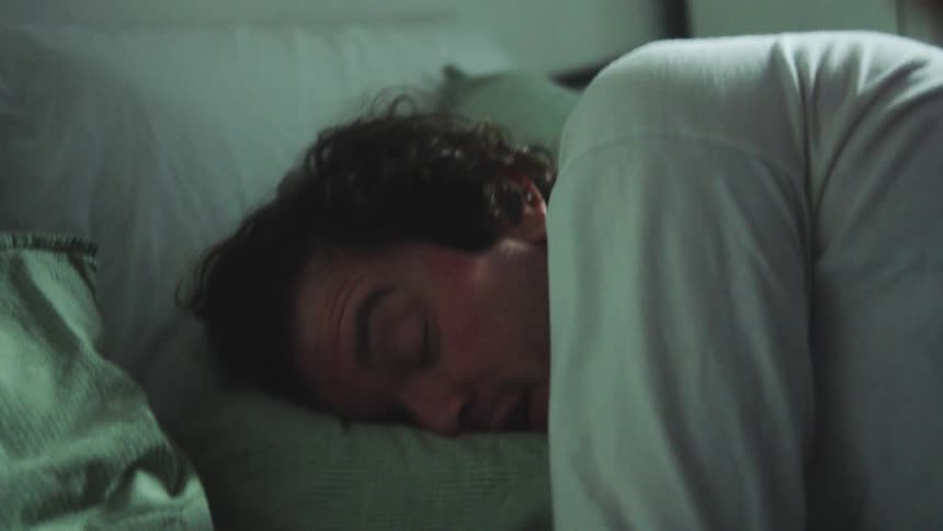 Close up of a couple conversing while lying in bed in a bedroom at dawn