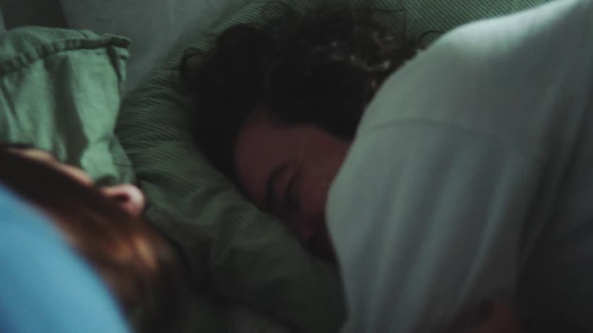 The woman is trying to get the man to wake up