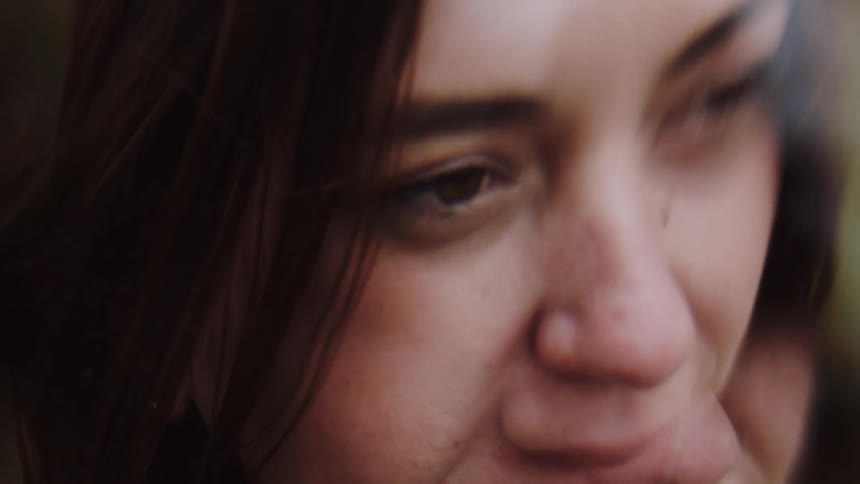 This closeup video focuses on the face of a woman with dark hair showing her looking up and to the side with a slight subtle smile or thoughtful expressionthe framing is tight on her eyes and nose and in the last few moments a portion of a green