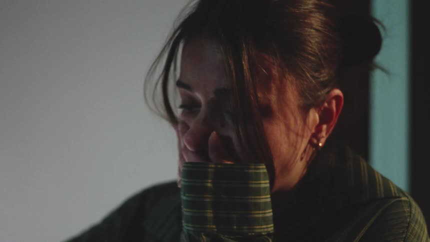 Woman with visible tears on her face head slightly tilted downward in an indoor setting with soft lighting