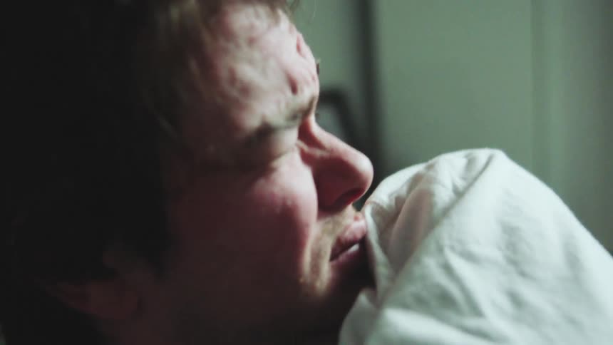 Man lying in bed with his face tightened upon waking
