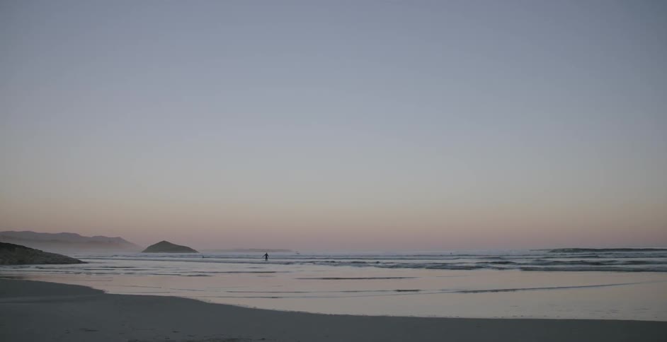 Person walks on the beach at sunrise