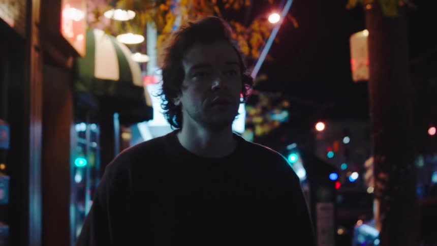 Person standing on urban street lit by signs and vehicle lights